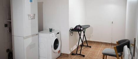 A compact laundry room with a washing machine, a dryer, and an ironing board.