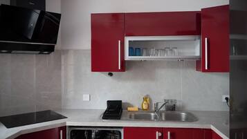 A kitchen with red cabinets, a black microwave, and a built-in dishwasher.
