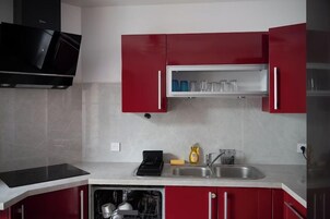 Una cocina con armarios rojos, un microondas negro y un lavavajillas integrado.
