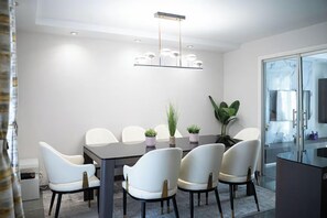 Un espace de salle à manger moderne avec une table ronde, des chaises blanches et un luminaire central.