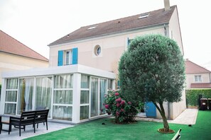 A modern house with a conservatory, a well-maintained lawn, and a large tree. - Villa Alexandre Dumas (Bussy-Saint-Georges)