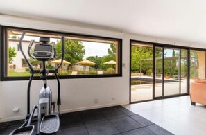 A modern room with a stationary bike, large windows, and a view of a garden. - Villa Alexandre Dumas (Bussy-Saint-Georges)