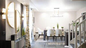 A modern dining area with a white table, four chairs, and a chandelier. - Villa Alexandre Dumas (Bussy-Saint-Georges)
