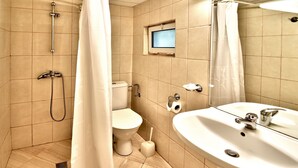 A bathroom with a shower, toilet, sink, and a small window. - Villas Holidays (Kiten)