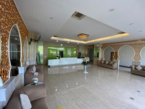 A hotel lobby with a reception desk, sofas, and a decorative wall. - Grand Bunda Hotel Syariah Bukittinggi Pba (Bukittinggi)