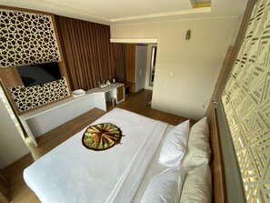 Una habitación de hotel con una cama grande, un escritorio, un espejo y un armario.
