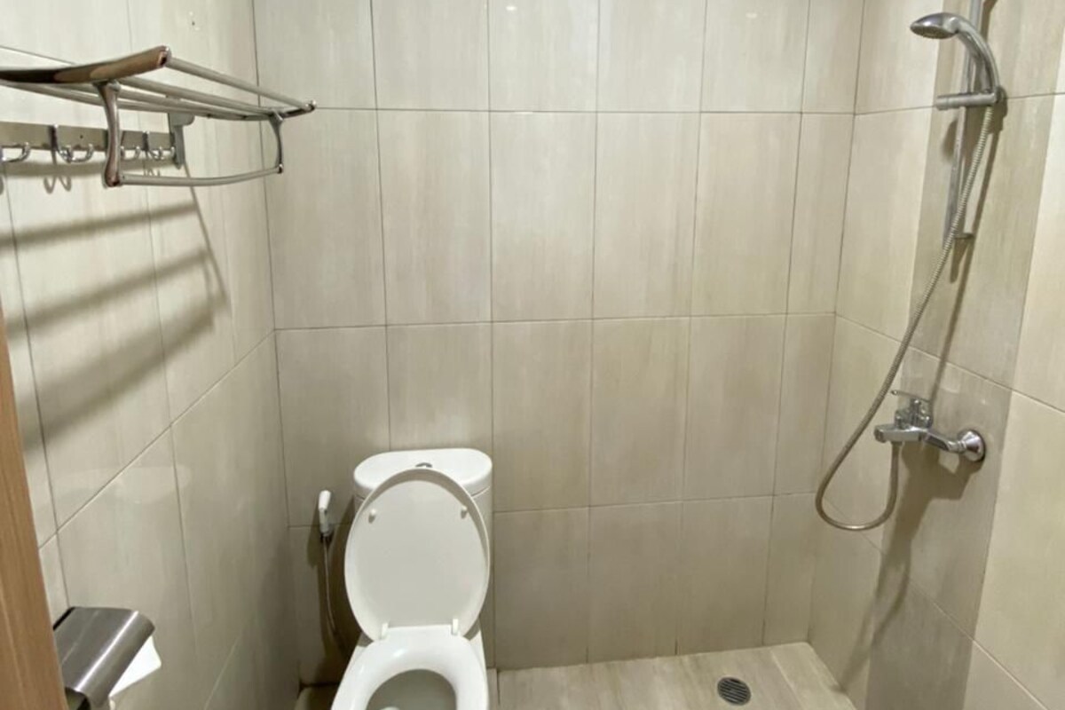 A small, tiled bathroom with a toilet, a shower, and a towel rack.