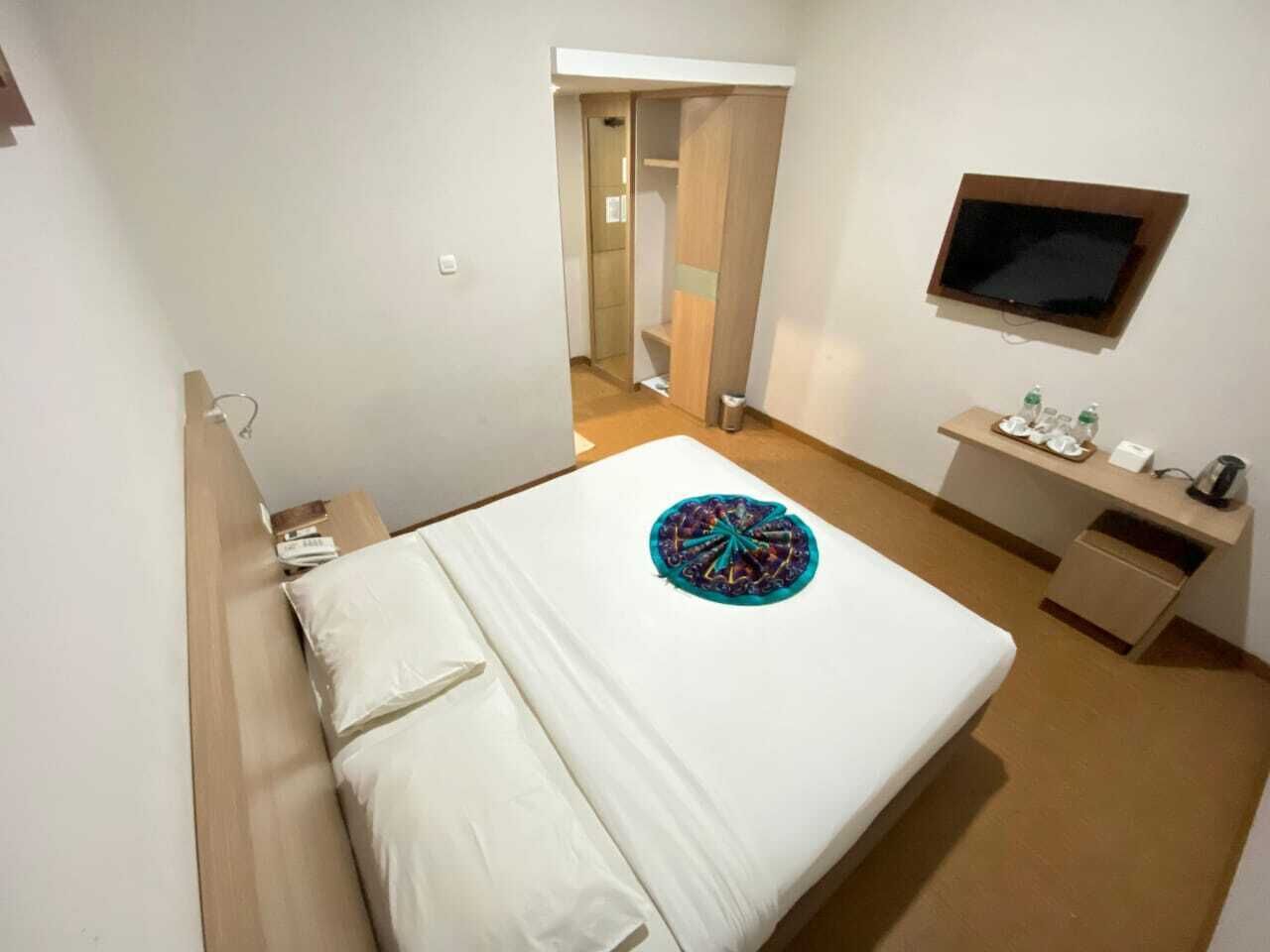 Ein Hotelzimmer mit Bett, Schreibtisch mit Fernseher und kleinem Badezimmer.