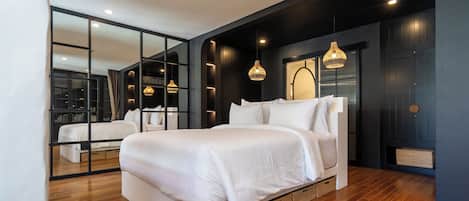 A modern bedroom with a large bed, wooden flooring, and a mirrored wall.