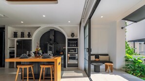 A modern kitchen with a dining area, built-in oven, and a cozy seating area with a sofa and a small table.