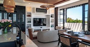 A modern living room with a flat-screen TV, comfortable seating, and a dining area with a table and chairs. - Kiara Ocean Place (Tibubeneng)