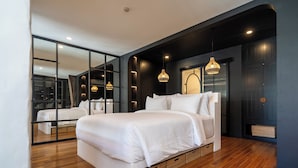A modern bedroom with a large bed, wooden flooring, and a mirrored wall.