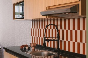 Une cuisine moderne avec un robinet noir, un évier en acier inoxydable et un pare-éclaboussures à motifs.
