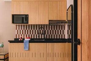 Une cuisine avec des meubles en bois, un four à micro-ondes, un dosseret à carreaux et un robinet noir.