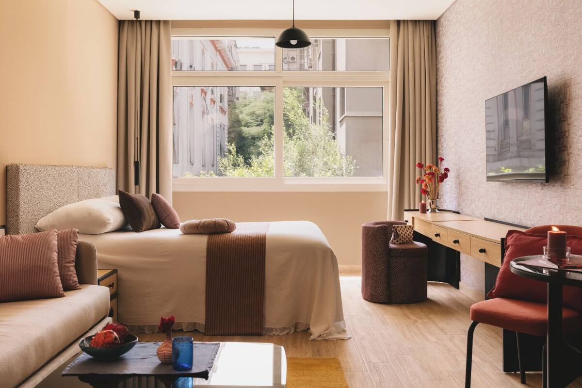 Una habitación de hotel moderna con una cama, un sofá, un escritorio y un televisor.