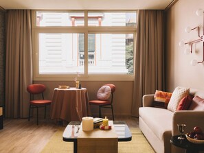 Un salon confortable avec un canapé, deux fauteuils, une table basse et une fenêtre avec des rideaux.