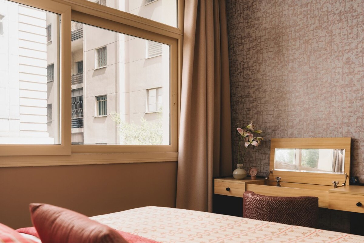 Une chambre d’hôtel avec un lit, un bureau et une fenêtre avec des rideaux.