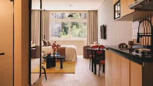 Una habitación de hotel moderna con cama, zona de comedor y cocina.