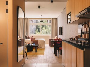 Una habitación de hotel moderna con cama, zona de comedor y cocina.