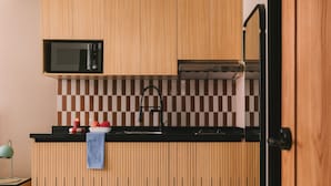 Una cocina con armarios de madera, microondas, salpicadero a cuadros y grifo negro.