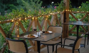 An outdoor dining area with tables and chairs, surrounded by wooden structures and greenery. - Nungwi Turtle Cave Resort (Nungwi)