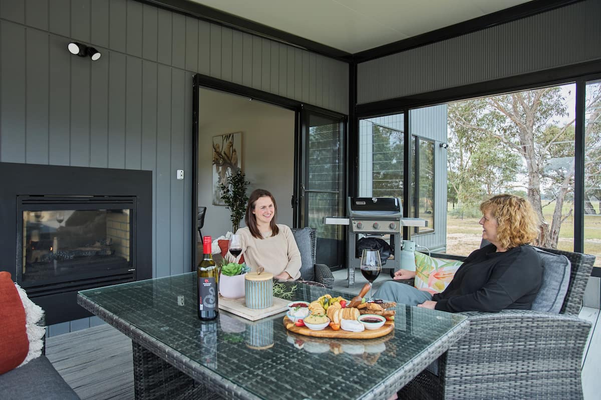 Un área de estar al aire libre con una mesa de vidrio, una chimenea y una parrilla.