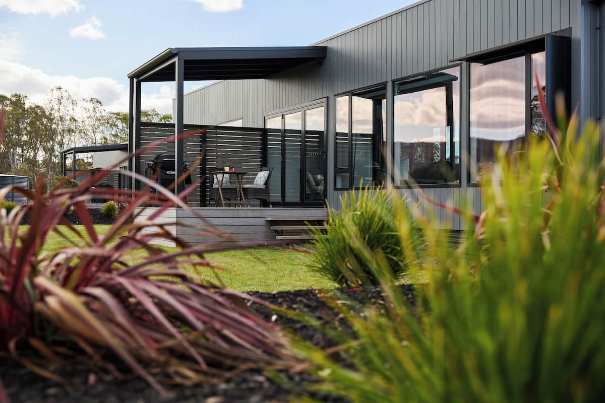 Una casa moderna con un espacio exterior cubierto, un patio amoblado y vistas del paisaje circundante.
