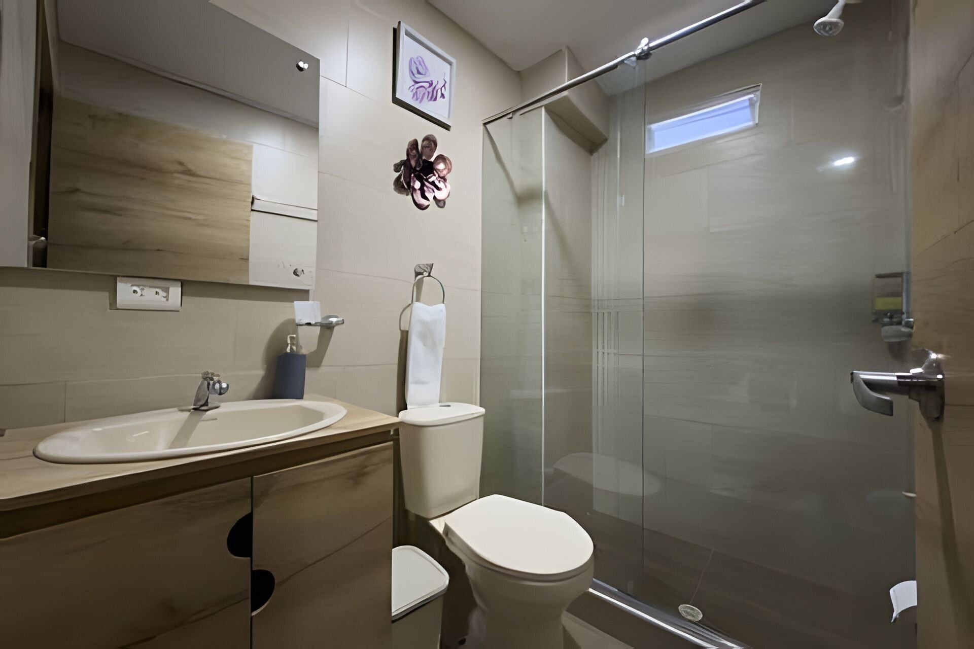 Un baño moderno con cabina de ducha de vidrio, lavamanos e inodoro.