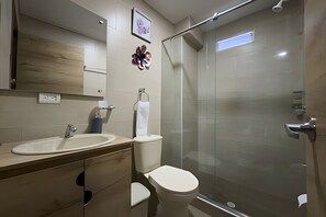Een moderne badkamer met een douchecabine van glas, een wastafel en een toilet.