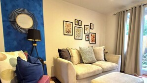 A modern living room with a blue accent wall, a round mirror, a sofa set, a pink armchair, and a rug. - Elegant 2-Bed Home - Prime City Centre Location (Leicester)