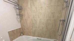 A bathroom with a bathtub, toilet, and shower. - Elegant 2-Bed Home - Prime City Centre Location (Leicester)