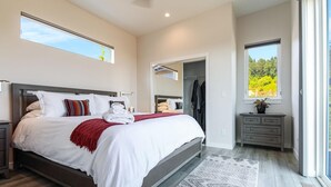 A modern bedroom with a large bed, a walk-in closet, and a view of greenery through the window. - The View House at Bryn Mawr Vineyards (Salem)