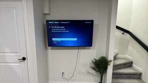 Seinälle asennettu litteänäyttöinen televisio, jonka valkoisella taustalla näkyy QR-koodin aktivointiruutu.