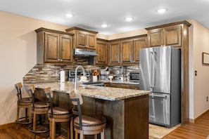 A modern kitchen with wooden cabinets, a stainless steel refrigerator, and a granite countertop. - Fantastic 3 Bd Lake Condo, 2 Min to Silver Dollar City (Branson)
