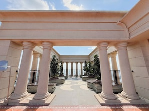 A covered walkway with columns and potted plants.