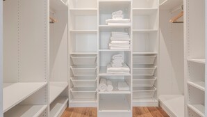 A walk-in closet with multiple shelves and hanging spaces, some with folded towels. - Blueground | Oberkampf, washer, nr Canal (Paris)