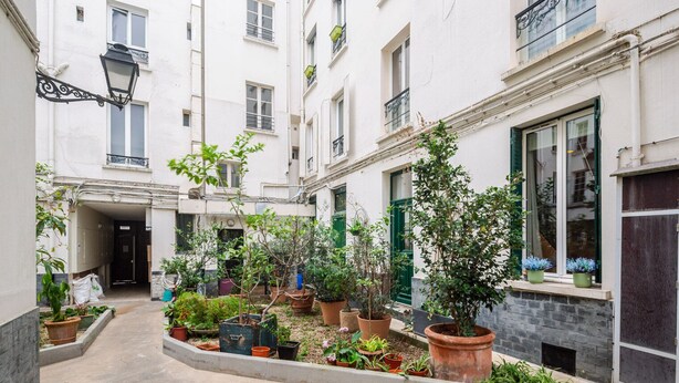 A narrow courtyard with potted plants and a pathway. - Blueground | Oberkampf, washer, nr Canal (Paris)