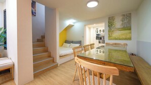 Un interior moderno con una escalera, un comedor con mesa de vidrio y una cama con vistas.