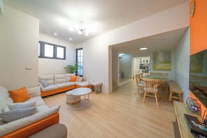 A modern living room with a sofa, coffee table, and dining area.