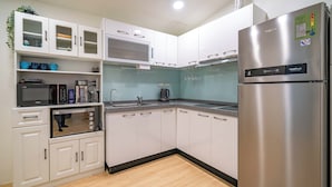 Una cocina moderna con armarios blancos, un refrigerador de acero inoxidable, un microondas y una cafetera.
