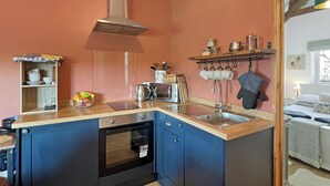 Uma cozinha compacta com forno embutido, exaustor de aço inoxidável e bancada de madeira.