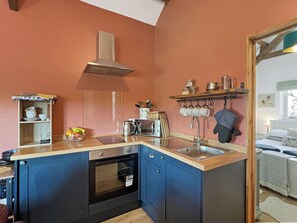 Eine kompakte Küche mit Einbauofen, Edelstahl-Dunstabzugshaube und Holz Arbeitsplatte.