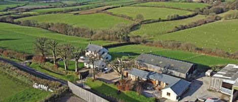 A rural property with a main house, a barn, and a fenced field with sheep.