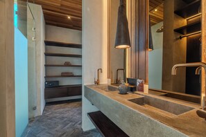 A modern bathroom with a large mirror, a stone sink, and wooden shelves. - Sirocco Villas Pererenan (Canggu)