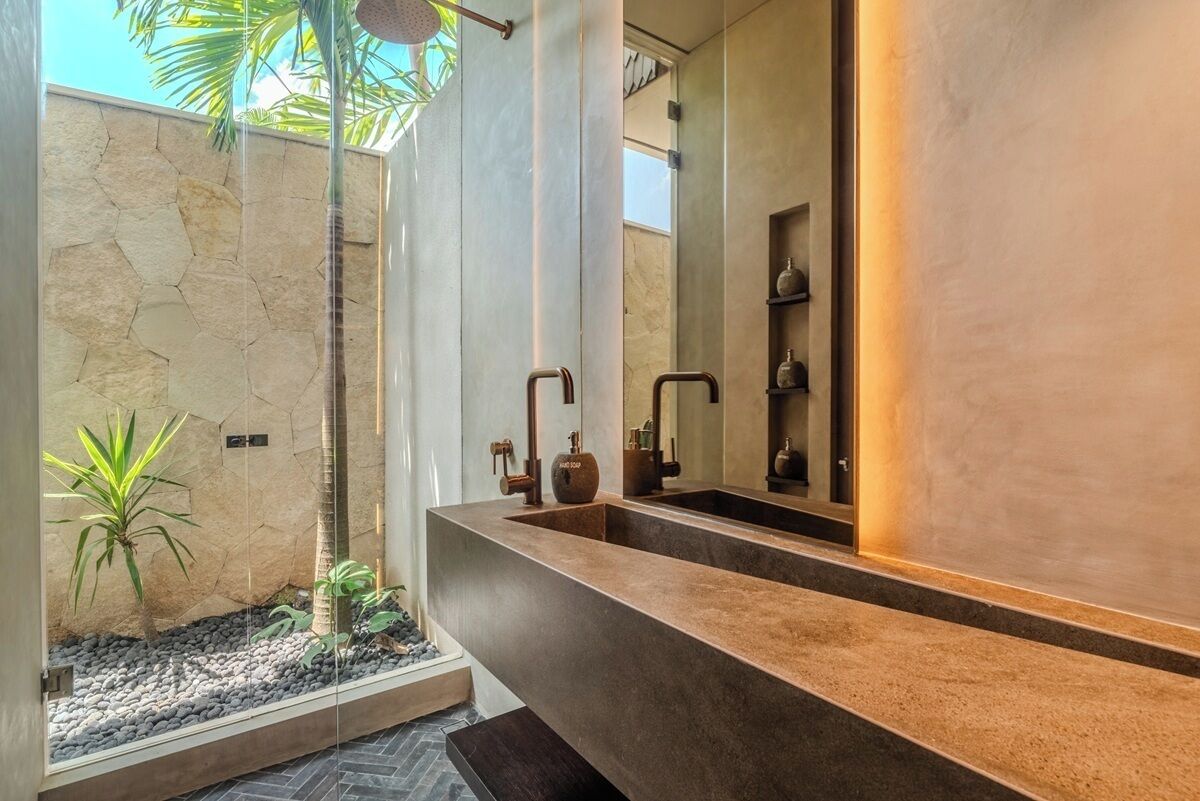 A modern bathroom with a large mirror, a stone wall, and a small indoor garden.