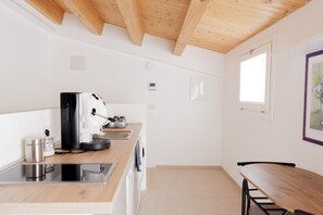 Eine moderne Küche mit Holzbalken, einer Kaffeemaschine und einem Essbereich mit Tisch und Stühlen.