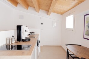 Eine moderne Küche mit Holzbalken, einer Kaffeemaschine, einem Spülbecken und einem Fenster.