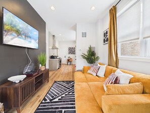 A modern living room with a sofa, a coffee table, and a TV mounted on the wall.