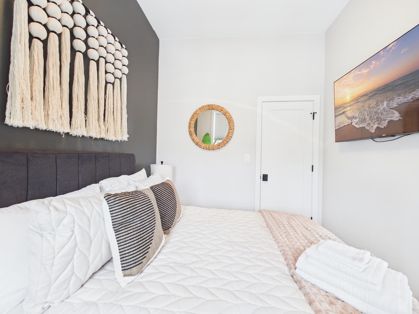 A bedroom with a bed, a wall-mounted mirror, a door, and a painting.