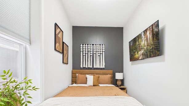 A bedroom with a bed, a nightstand, a wall-mounted light fixture, and a framed picture.